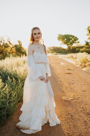 A ruffled white dress catches sunlight on a desert trail during golden hour.