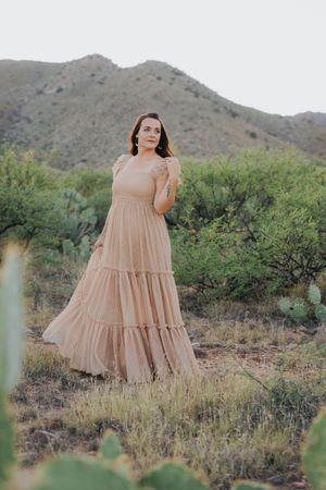 A peach-colored tiered dress stands out against the rugged desert landscape.