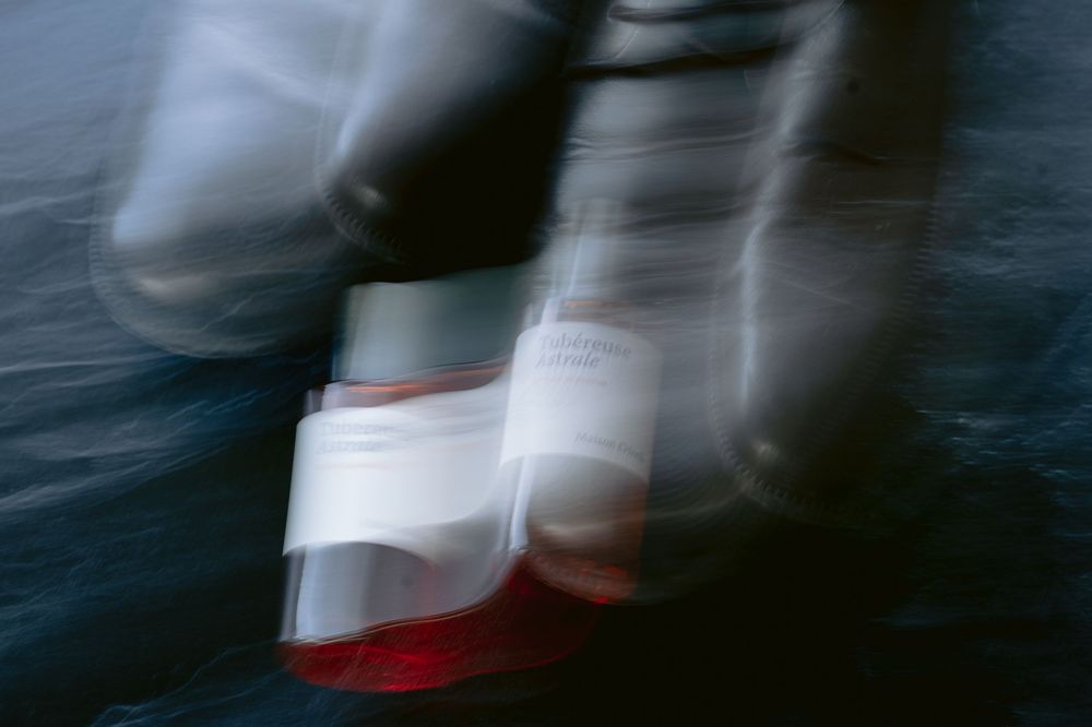 Blurred motion of five figures in white and red clothing walking in a line against a dark background.