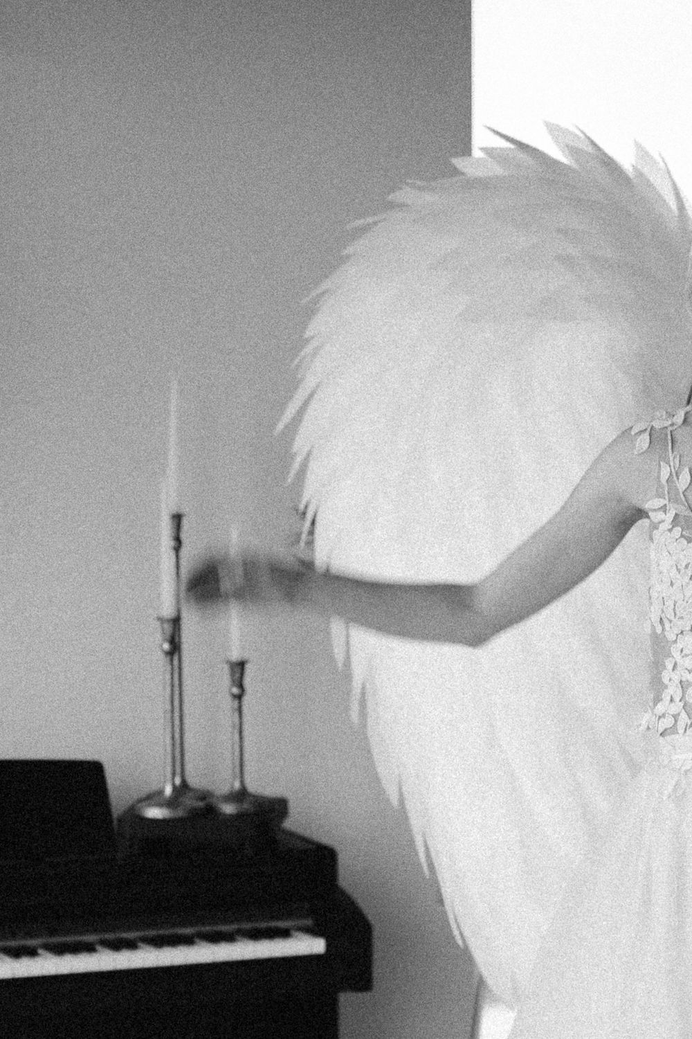 A series of black and white images showing a feathery silhouette against various interior backgrounds with candles and piano.