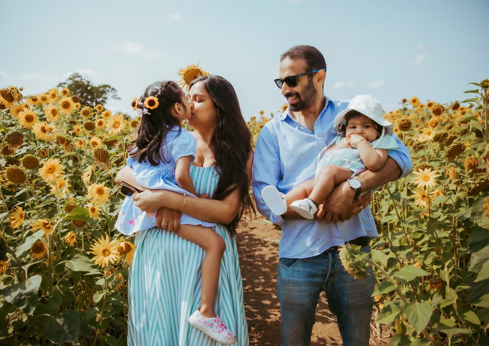 Family stands together in a vibrant sunflower field on a sunny summer day. During a family photography session in London