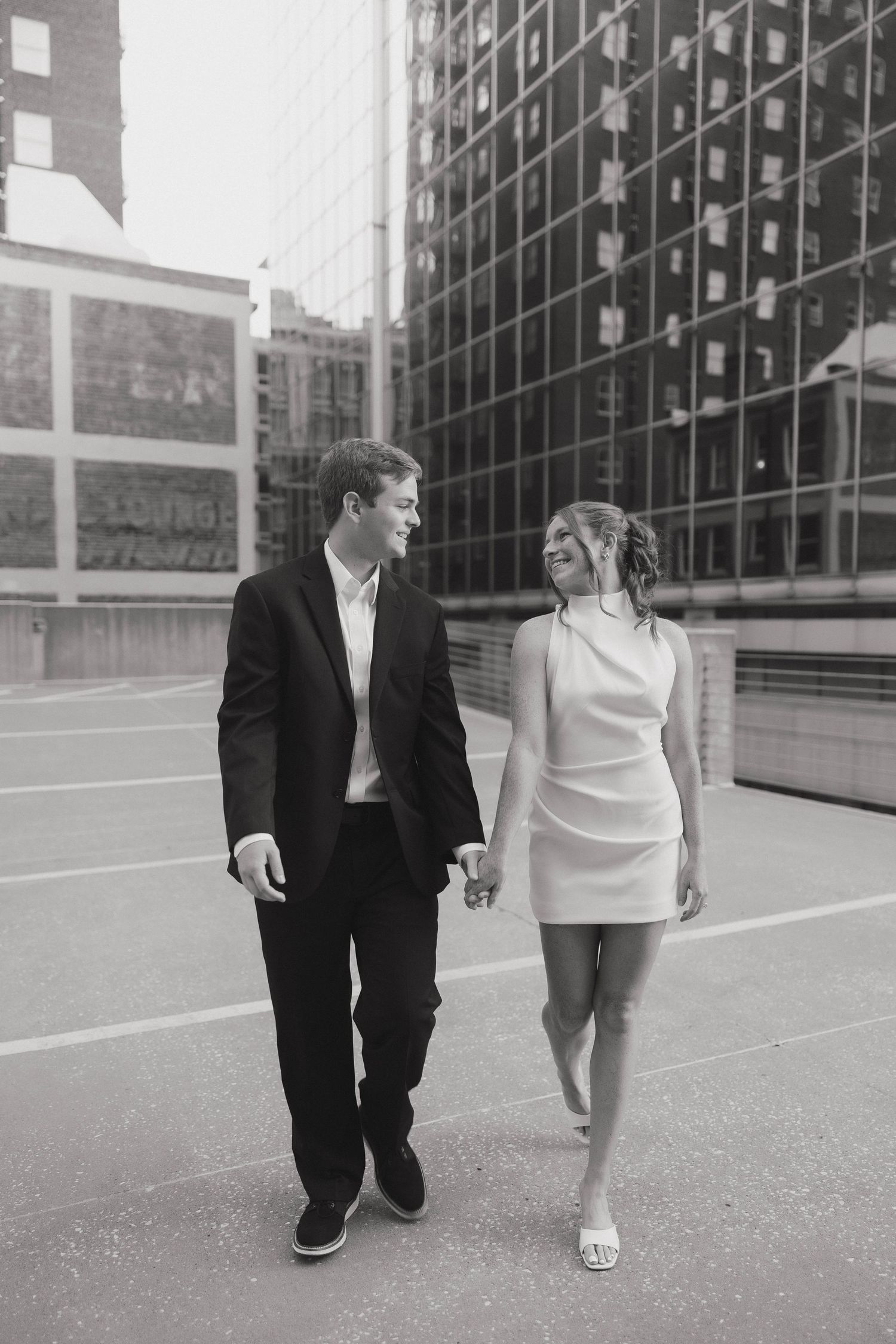 A couple walking together in an urban setting with modern office buildings in the background.