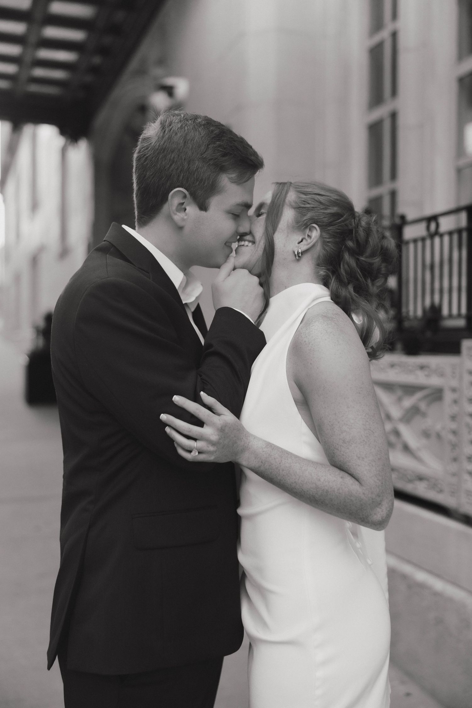 An intimate black and white portrait of a couple sharing a romantic moment in formal attire.