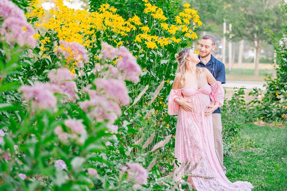 Pink dress surrounded by blooming flowers in a romantic garden setting during a sunny spring day.