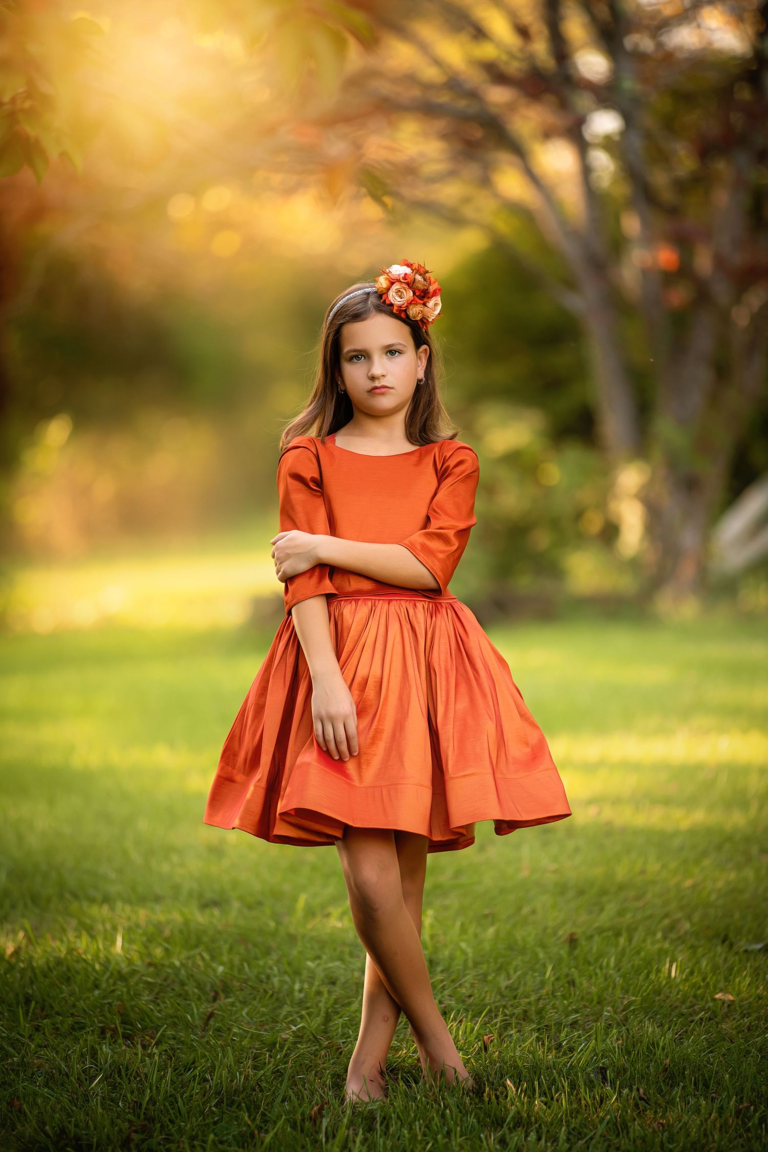 Autumn scene with figure in yellow vintage dress holding flowers in golden sunlight.