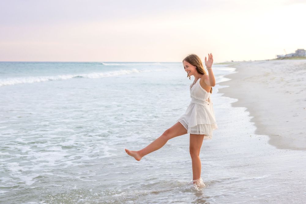 Playful beach portraits showing movement and joy along the shoreline at sunset.