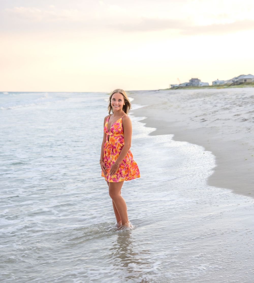 Beachside photos featuring a floral orange dress against the shoreline during golden hour.