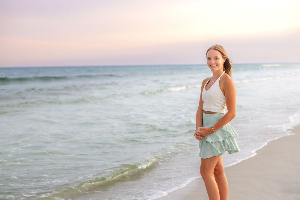 Lifestyle beach portraits with soft pastel sunset colors and gentle waves in the background.