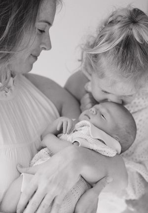 A tender black and white portrait of a family sharing an intimate moment with their newborn baby.