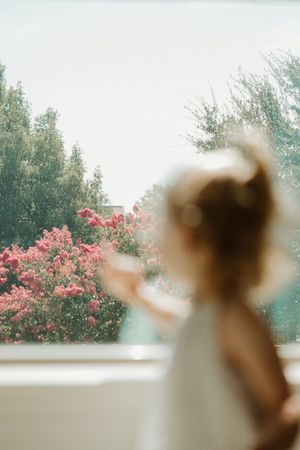 A dreamy silhouetted figure points toward vibrant pink flowering trees against a soft-focus natural backdrop.