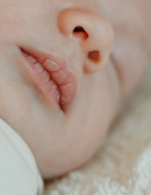 Extreme close-up macro photo showing delicate soft lips and nostril of sleeping baby in soft focus.