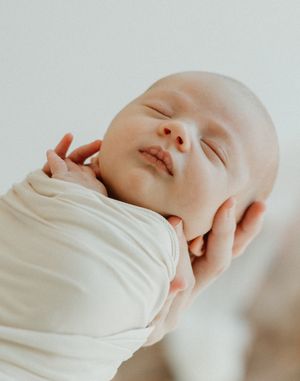 Three minimalist beige-toned images showing a peaceful sleeping infant wrapped in a soft white garment.