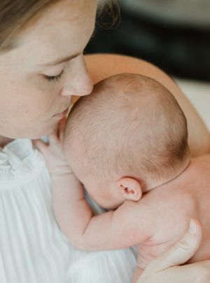 A tender moment captured between a baby and adult in soft, natural lighting showing gentle affection and bonding.