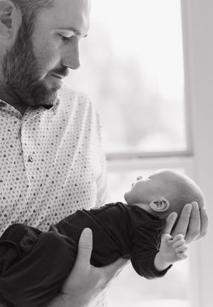 A tender moment showing gentle care and bonding with a newborn in black and white tones.