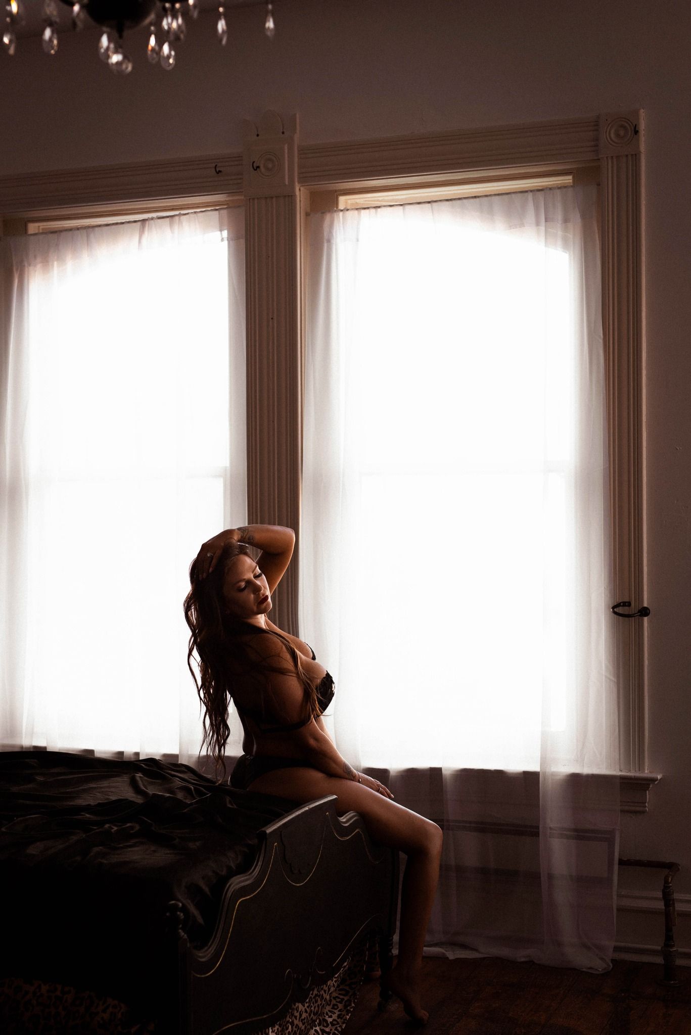 A portrait in dramatic lighting showing a woman wearing lingerie posing for her boudoir session