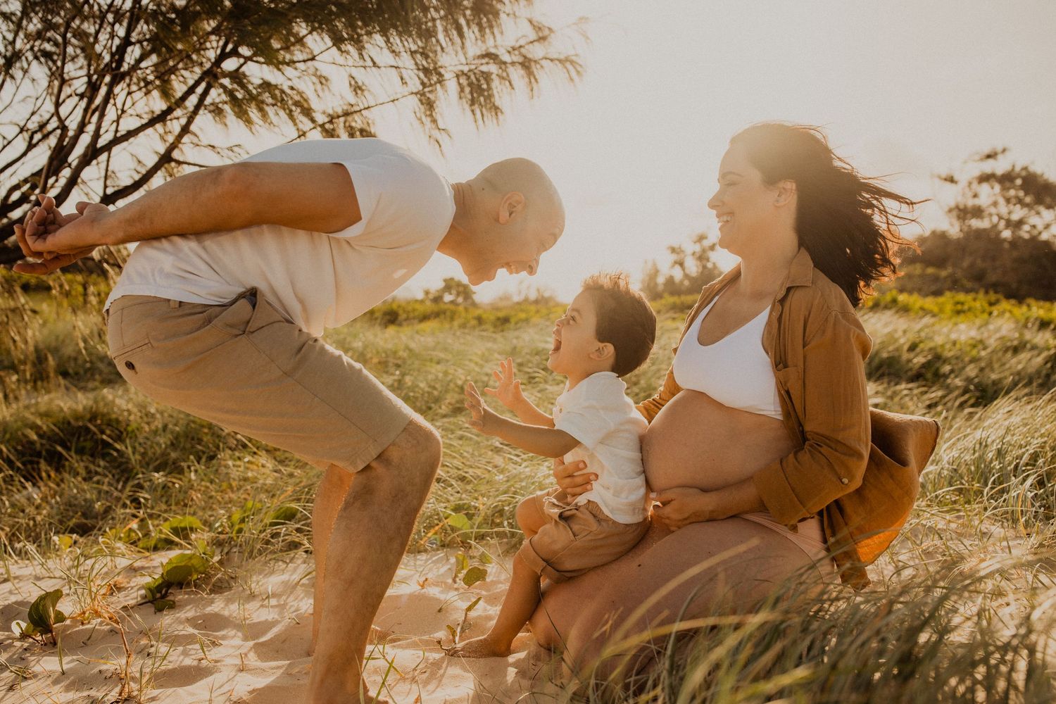 A joyful family spends quality time together on a grassy hill during golden hour at sunset.