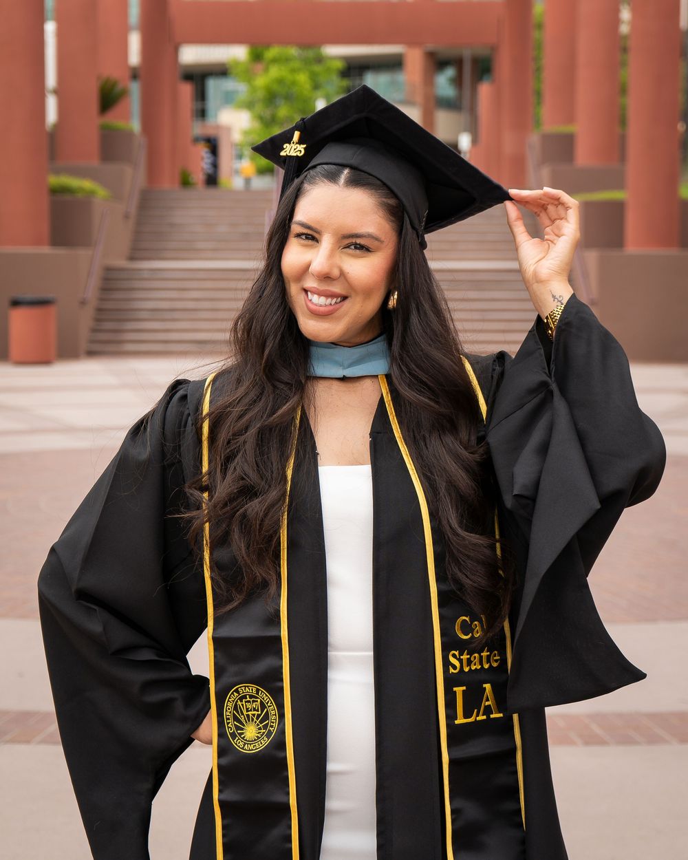 Close-up of graduate in cap and Cal State LA gown standing on campus steps.