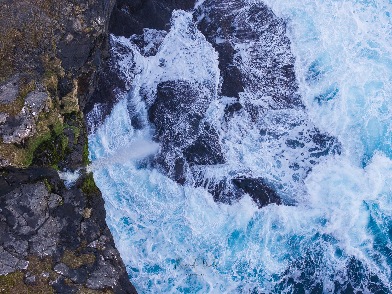 Aerial photograph above a waterfall spilling into the ocean. Faroe Islands landscape photograph.