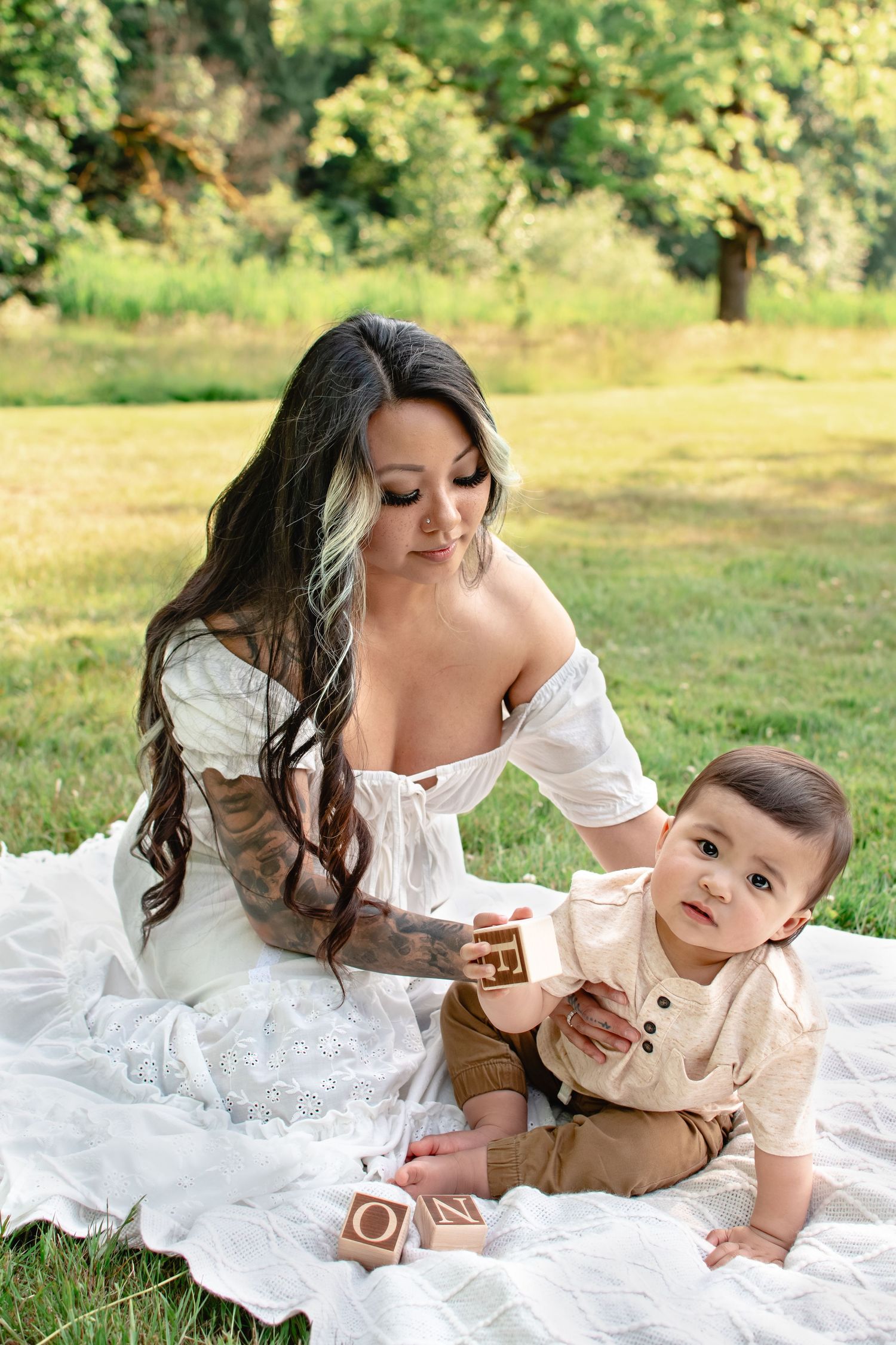Mom sitting with baby on white blanket in field at Flaming Geyser State Park
