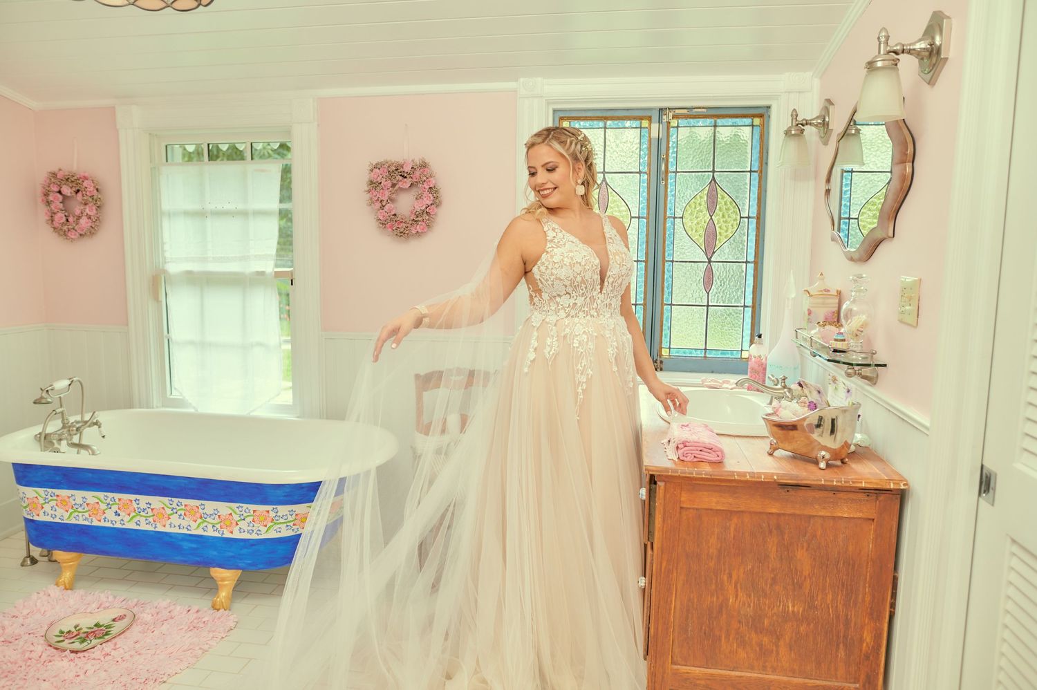 A stunning bridal scene in a pastel pink bathroom featuring a clawfoot tub and elegant wedding gown.