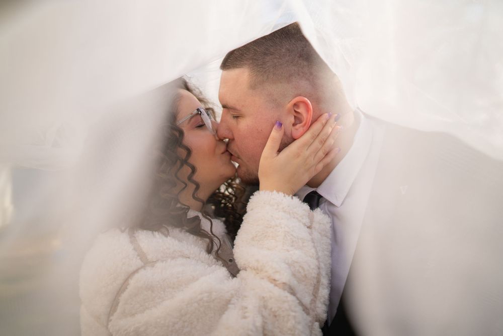 Intimate wedding couple moment captured against soft white background.
