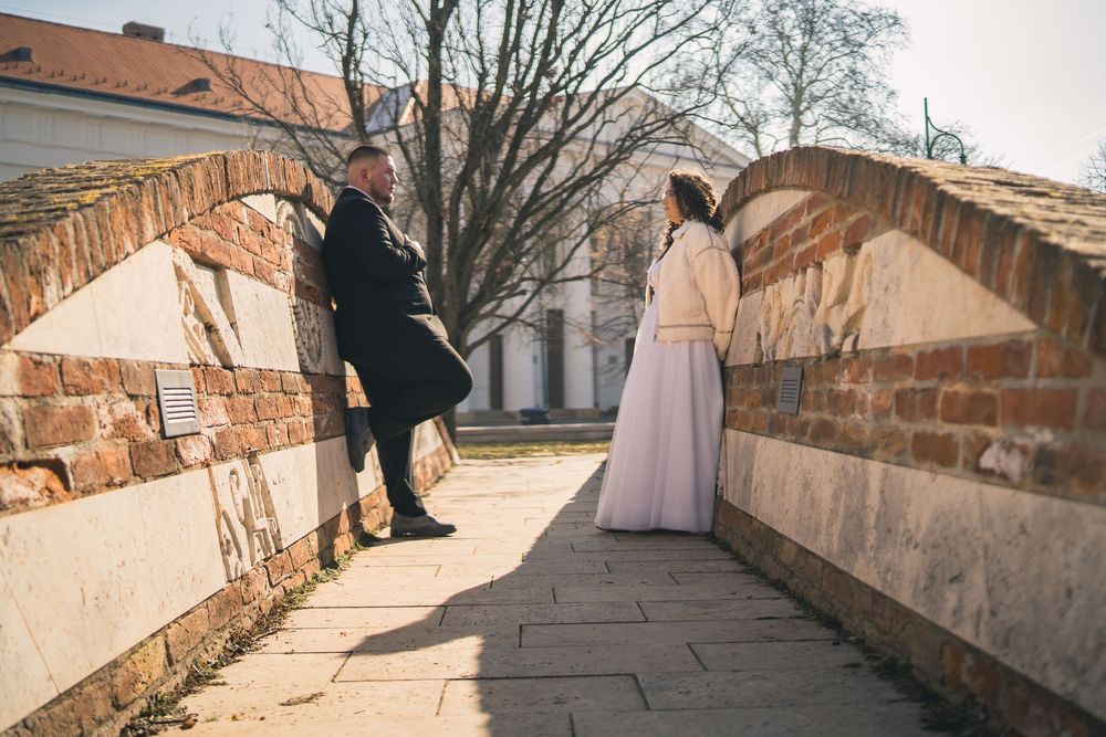 Winter wedding couple walking along historic stone wall pathway.