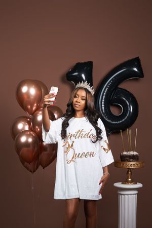Birthday celebration setup with rose gold balloons, number 6 balloon, and a decorative pedestal against brown backdrop.