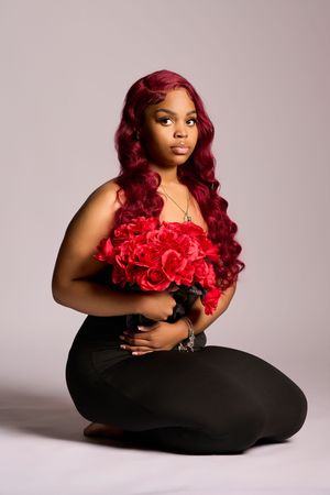 A glamour portrait series showing poses with bright red roses against a black dress on light studio background.