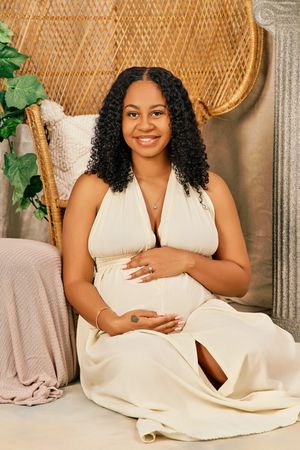 A collection of maternity portraits with someone wearing a white dress against a woven peacock chair and greenery backdrop.
