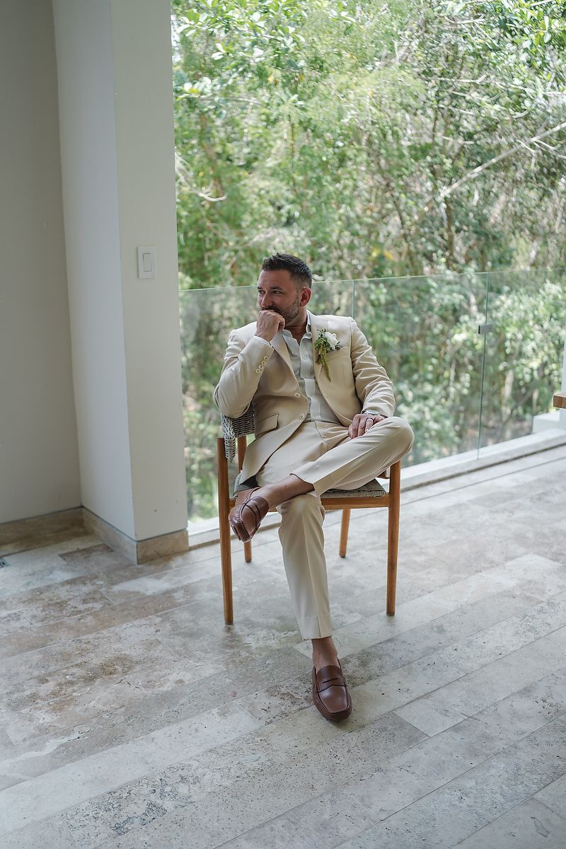 Groom sitting in beige suit before wedding at Fairmont Mayakoba Riviera Maya photography.