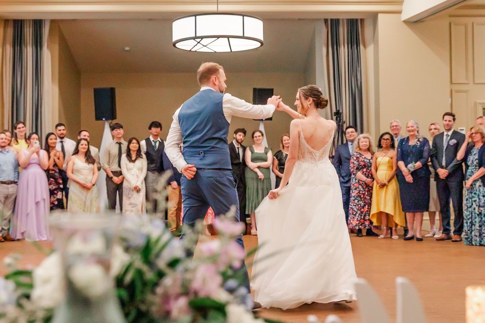 A couple shares their first dance at a wedding reception while guests watch from the sides of the ballroom.