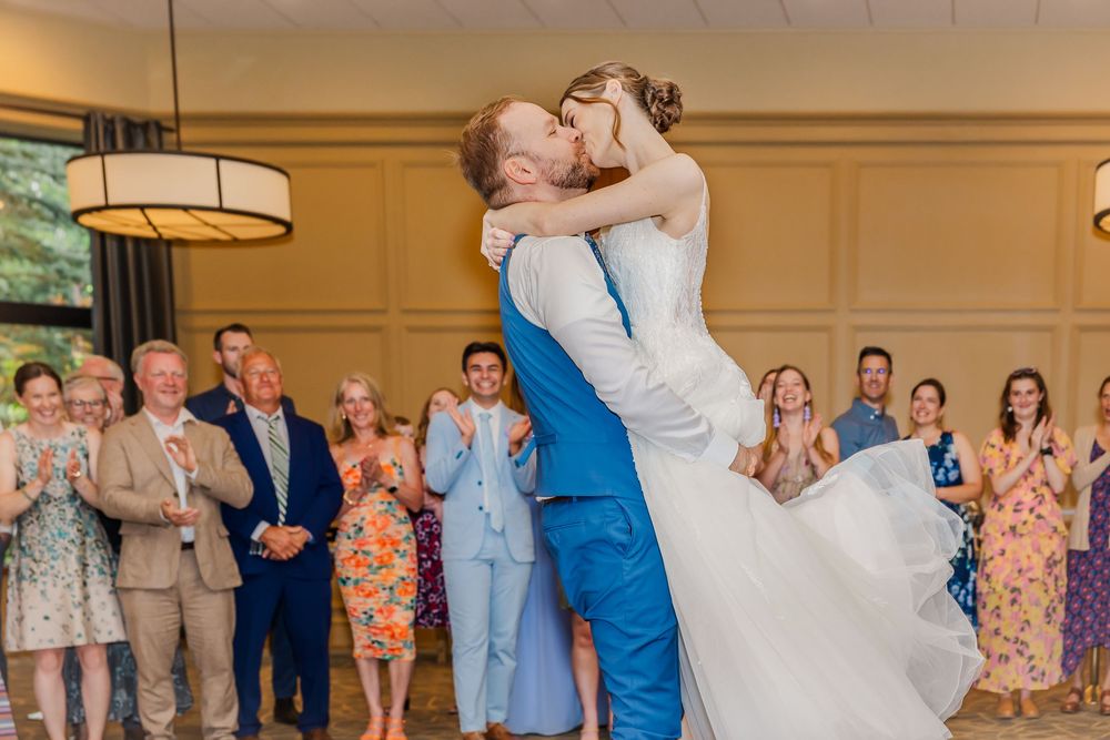 A romantic first dance at a wedding as guests clap and cheer in the background during the reception.