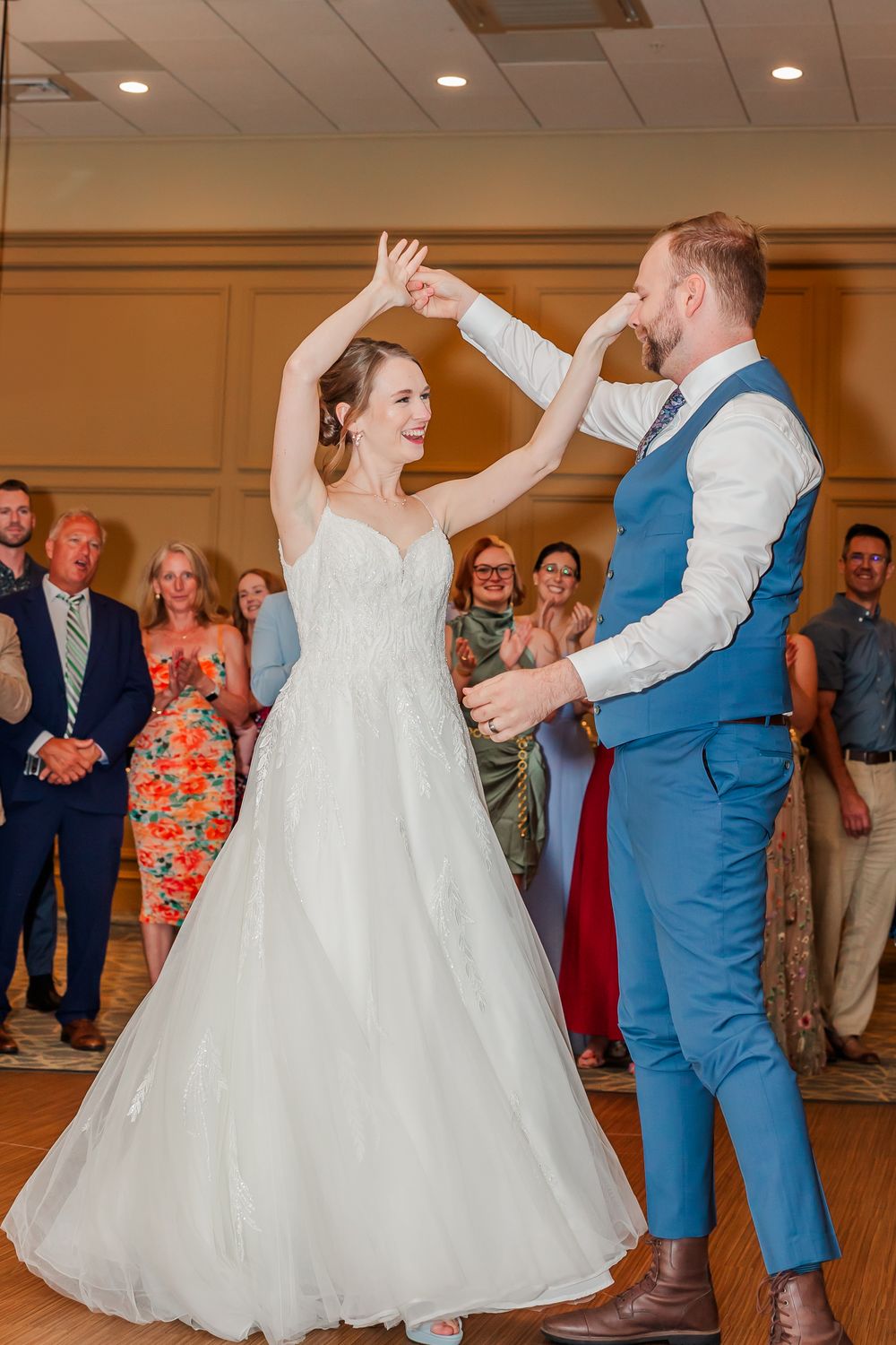 A couple joyfully dances together at their wedding reception while guests watch in the background.
