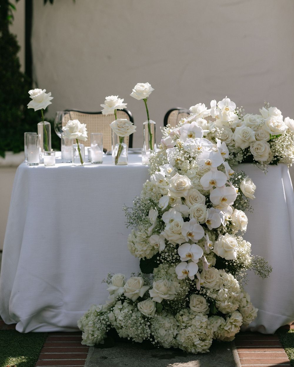 Sweetheart table with cascading white floral arrangement featuring orchids, roses, and baby's breath.