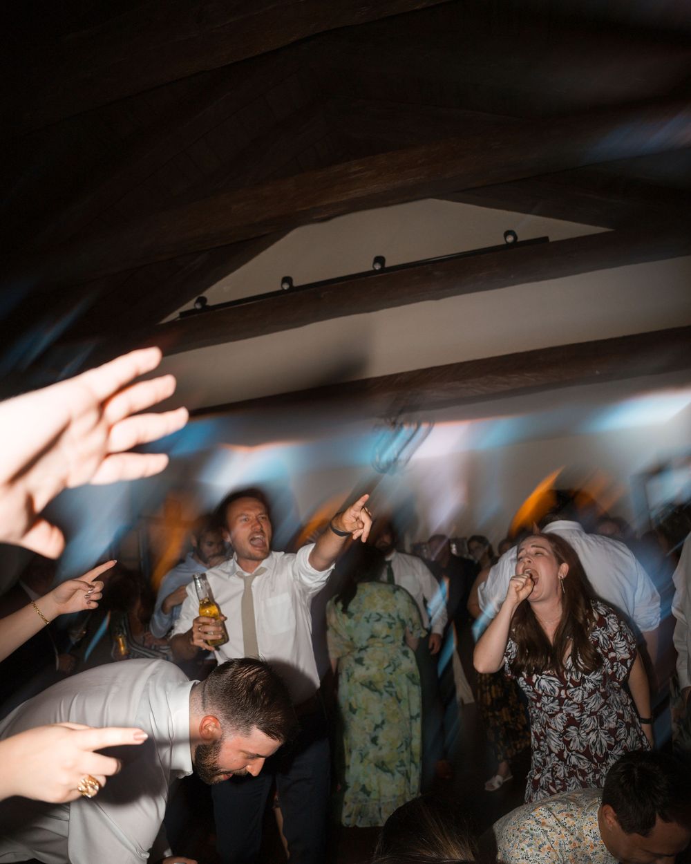 A group of people dancing and enjoying themselves at a party with dim lighting and hands raised in celebration.