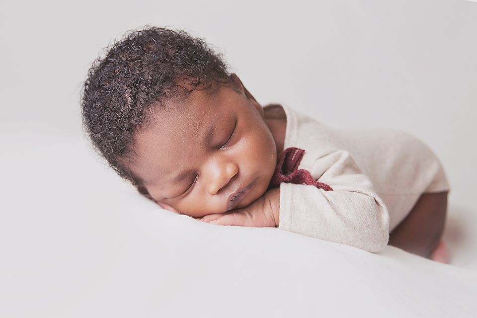 A sleeping newborn baby rests peacefully in soft white bedding while photographed from different angles.