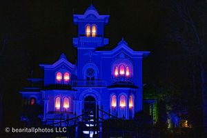 Gothic style building bathed in blue light with glowing pink windows at night.