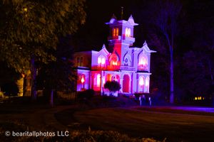 Victorian architecture dramatically lit in purple and red against dark night sky.