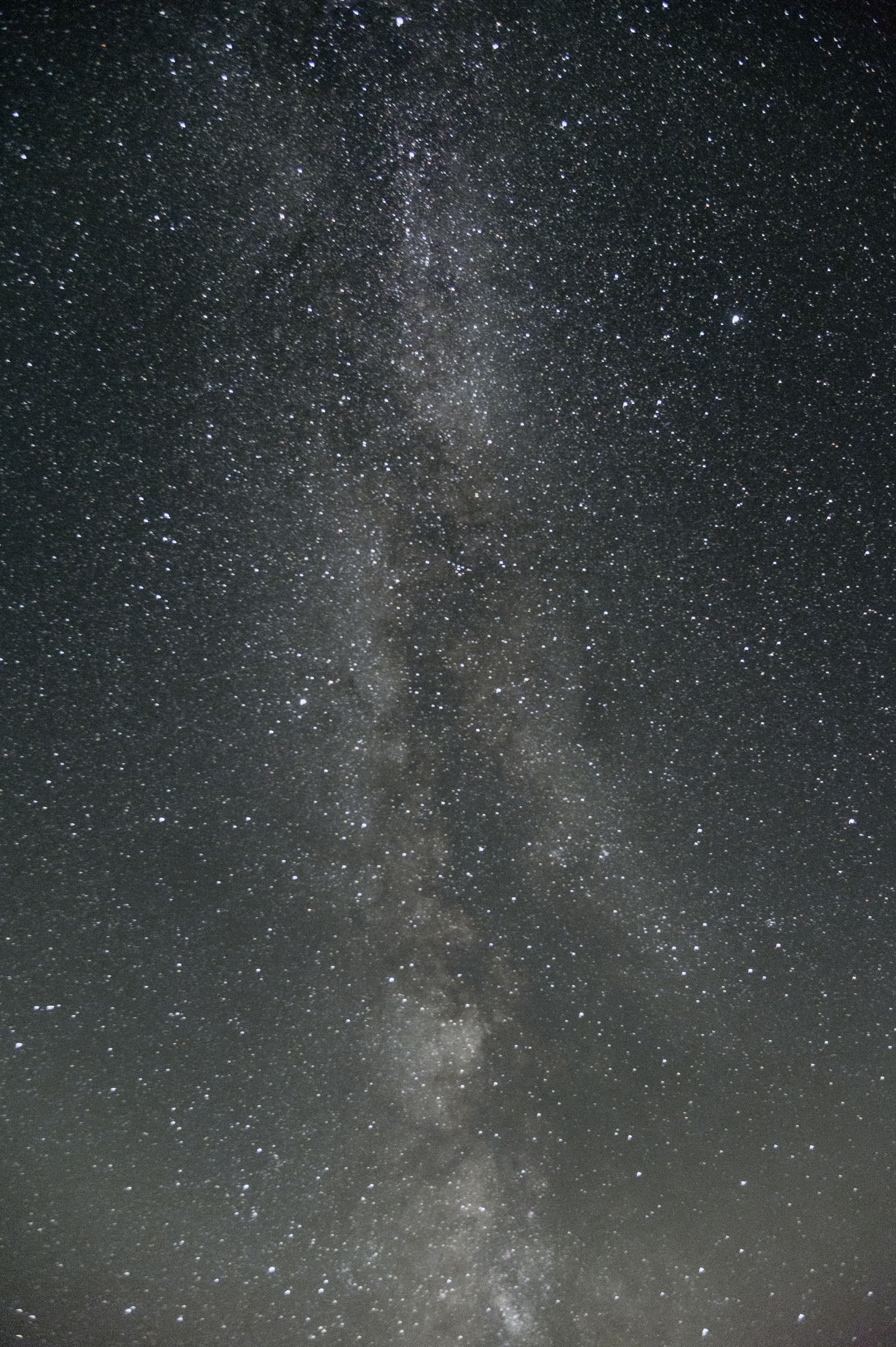 The Milky Way galaxy stretches across a dark night sky filled with countless stars.