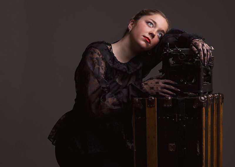 Dramatic black and white portrait series showing artistic poses against a dark background with vintage furniture.