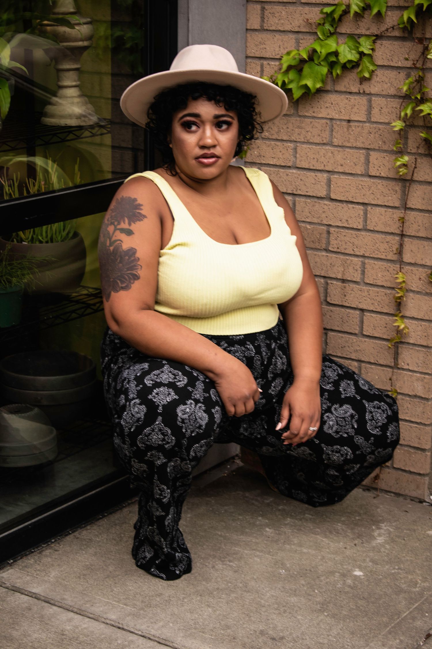 A series of fashion photos showing someone in a yellow tank top and patterned pants sitting on concrete steps.