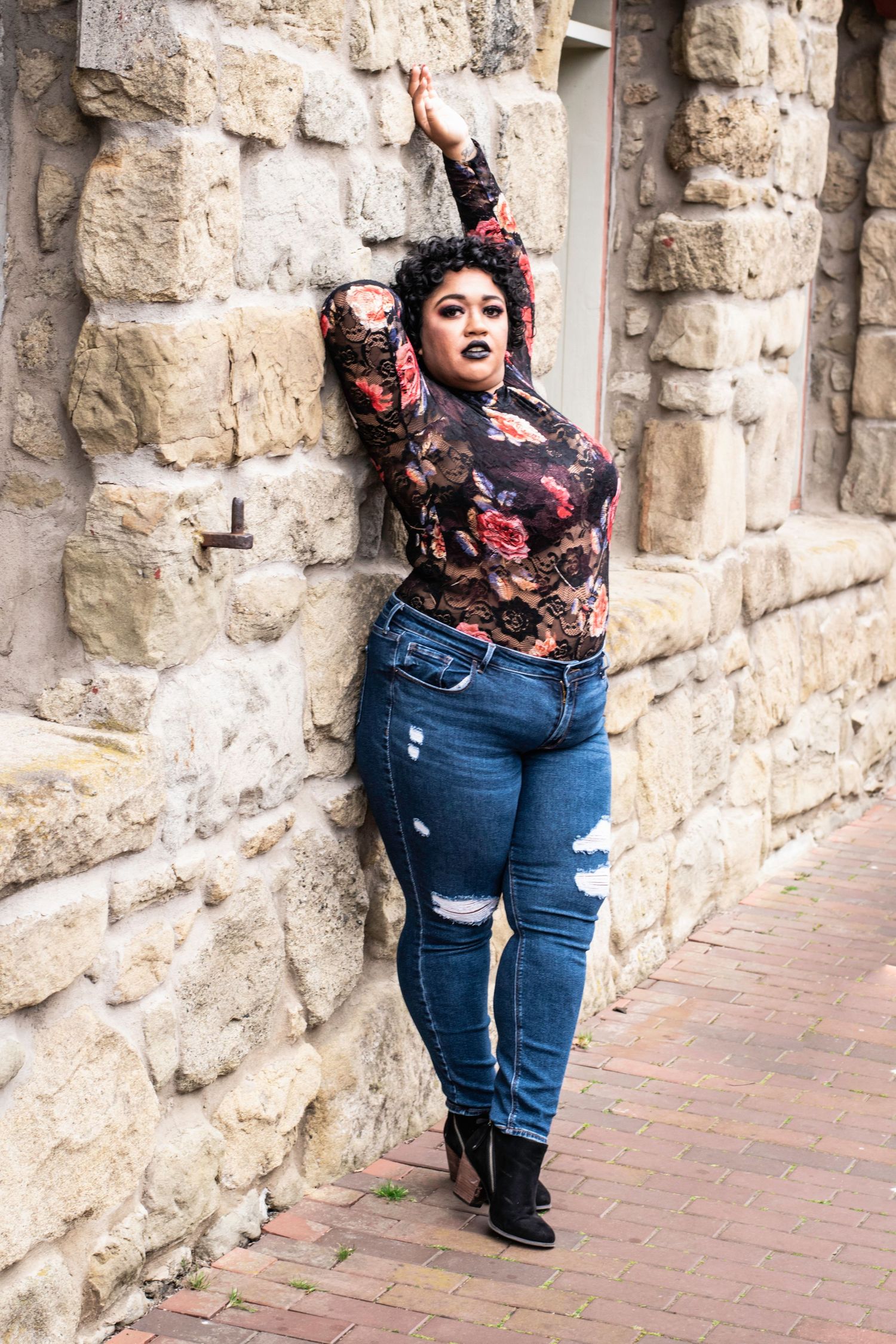 A series of three fashion photos showing a curvy model in ripped jeans and floral top posing against a stone wall.