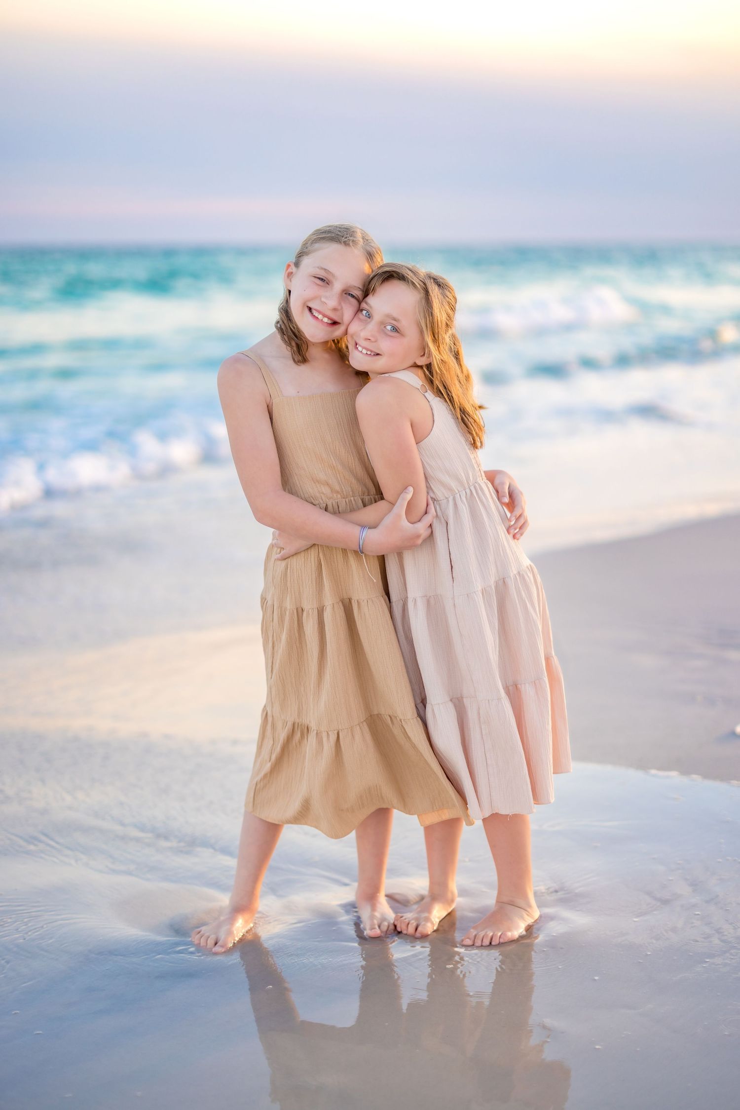 A family group walks together on a pristine white sand beach at sunset with ocean waves in the background.