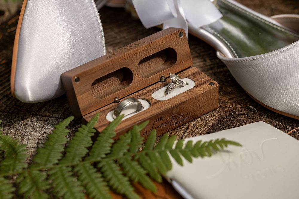 White bridal shoes arranged with delicate ferns and natural decor elements on wooden surface.