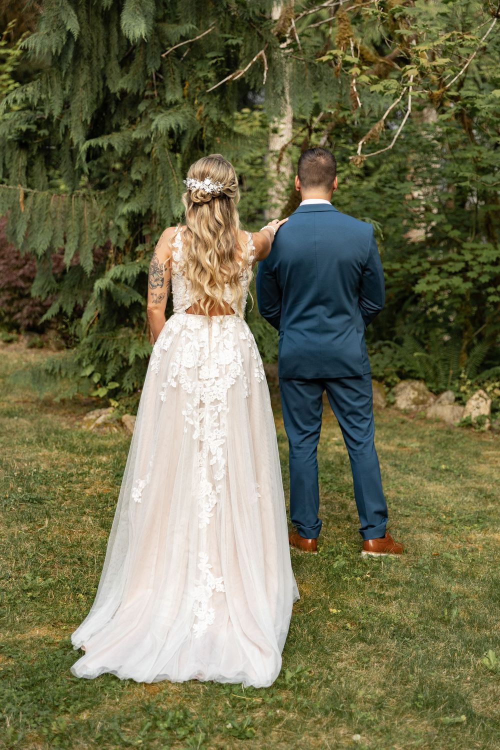 A couple in wedding attire walking through a lush garden setting.