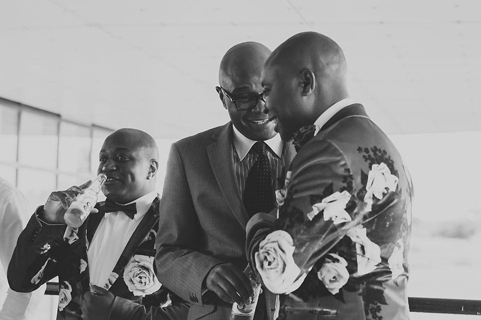 Black and white photo of groomsmen sharing joyful moments during wedding celebrations.