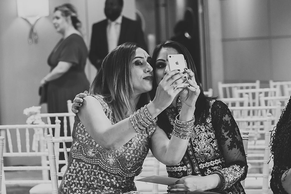 Wedding guests react emotionally during a ceremony while seated in white chairs at an elegant venue.