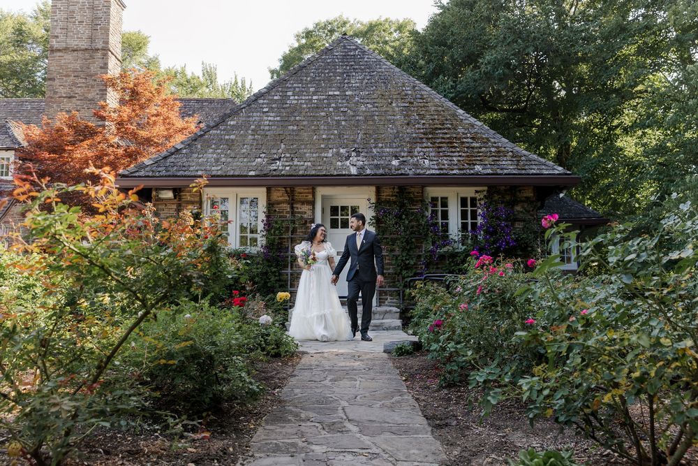 Bride and groom enjoy a stroll down a path in the garden at the cottage at the Riverwood Conservancy in Mississauga, Ontario.