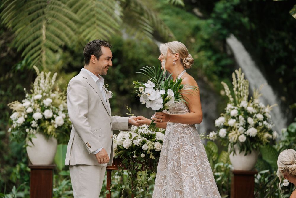 A couple shares a joyful moment during their wedding ceremony surrounded by elegant white floral arrangements.