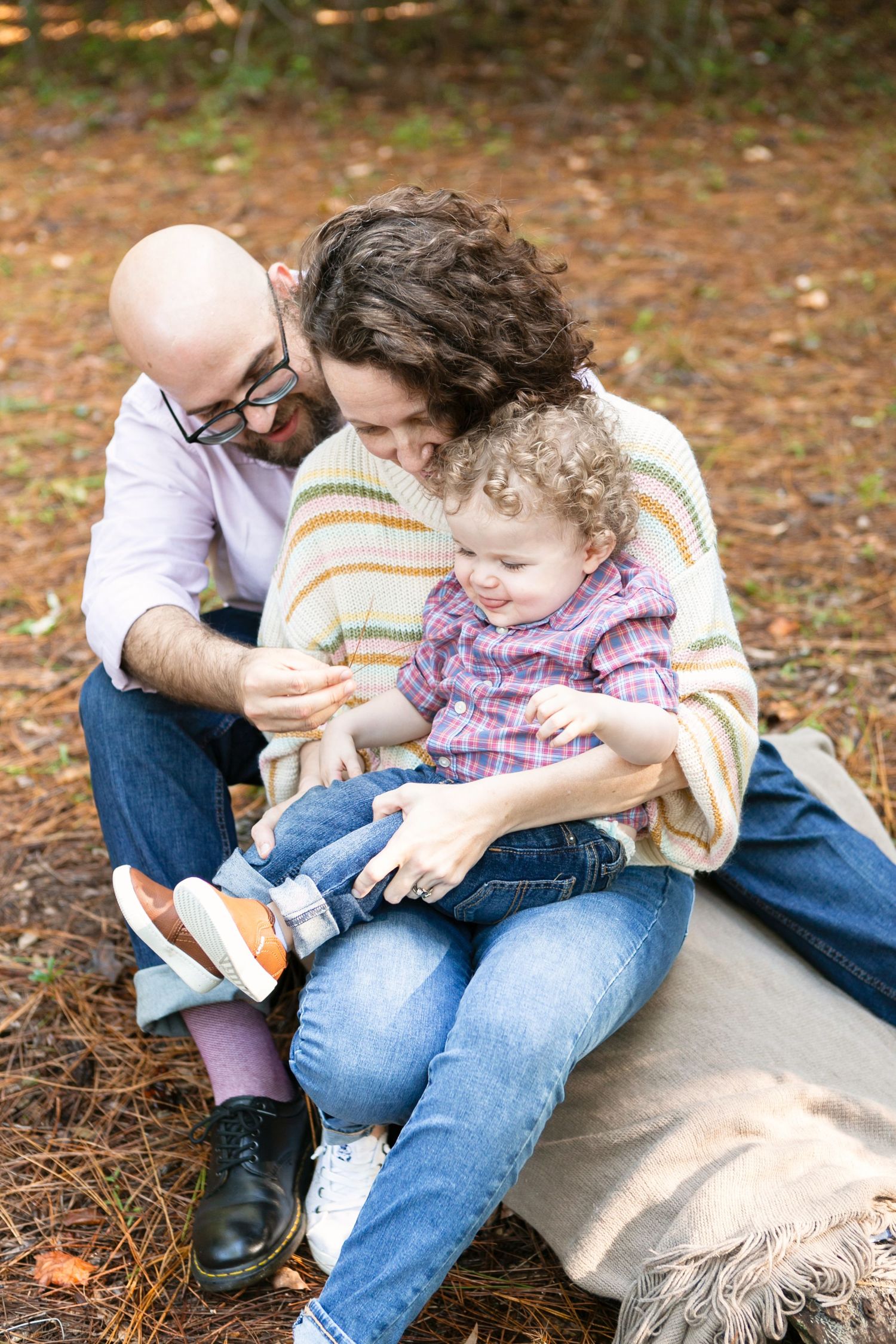 A parent and child sitting on fallen leaves outdoors in autumn. Orlando Family Photography, Sanford Family Photography